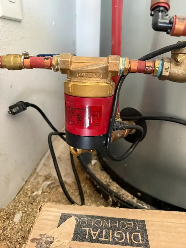 A red circulator pump on copper pipe with brass unions