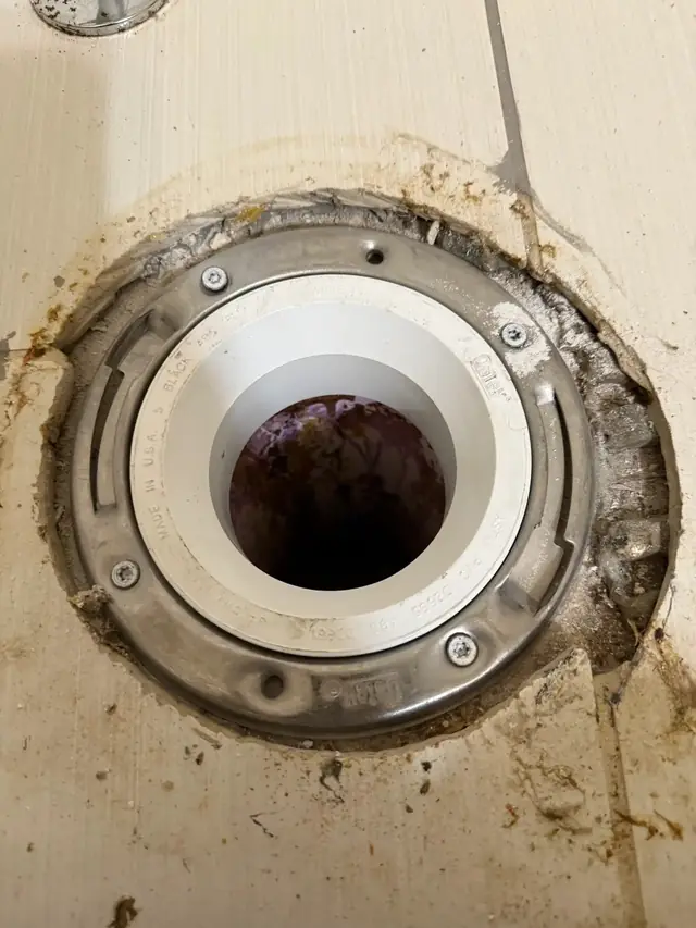 New PVC closet flange set in an old cast iron ring on a tiled bathroom floor