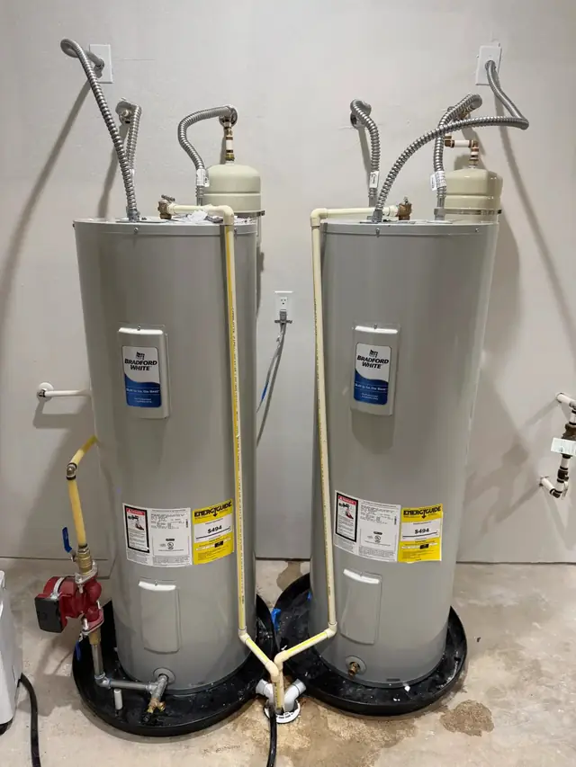 Two new Bradford White electric water heaters set level on drain pans with fresh braided supply lines